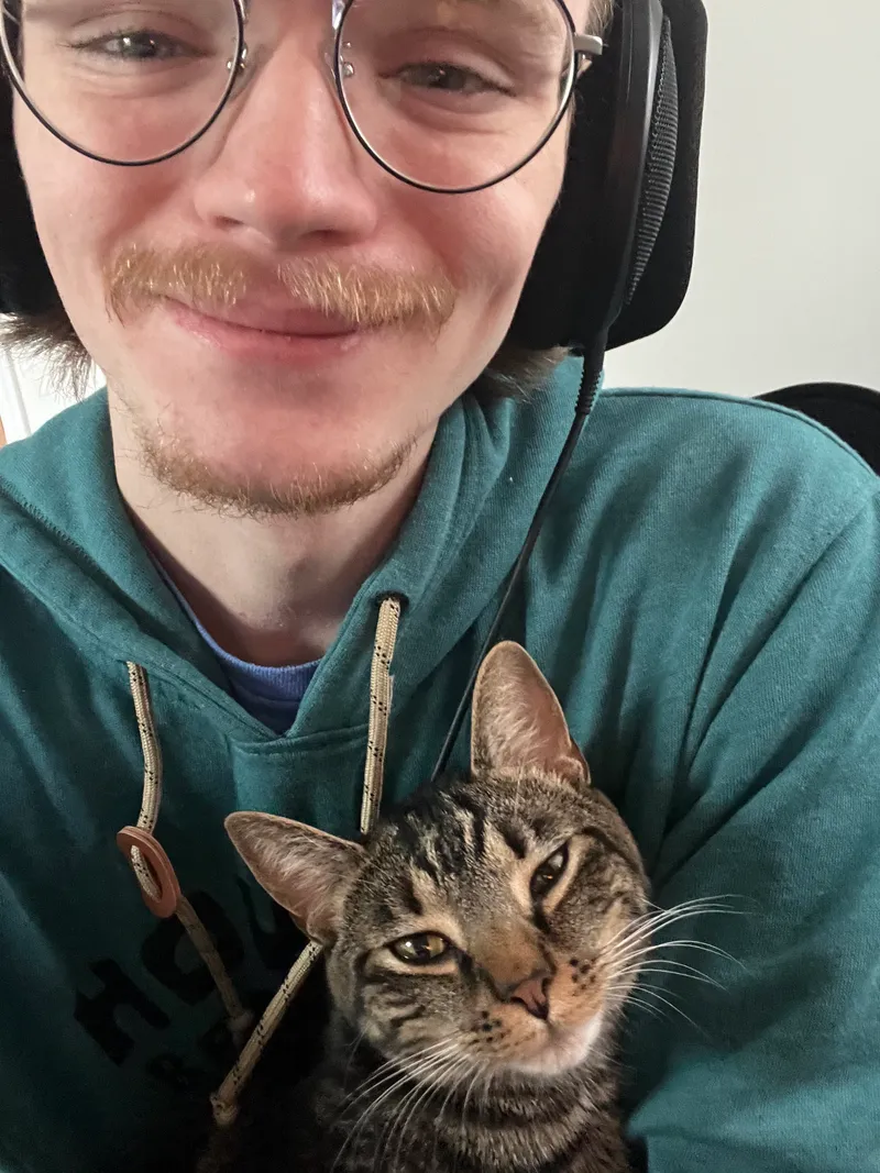 Jordan holding his cat Lacy, both smiling
